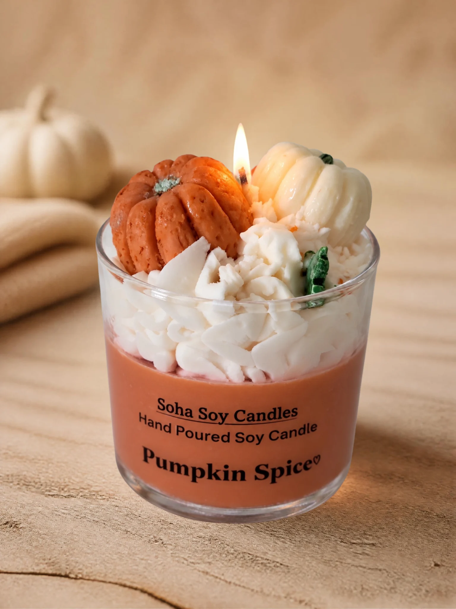 Burning Pumpkin Spice soy candle with pumpkin-shaped decorative wax toppers