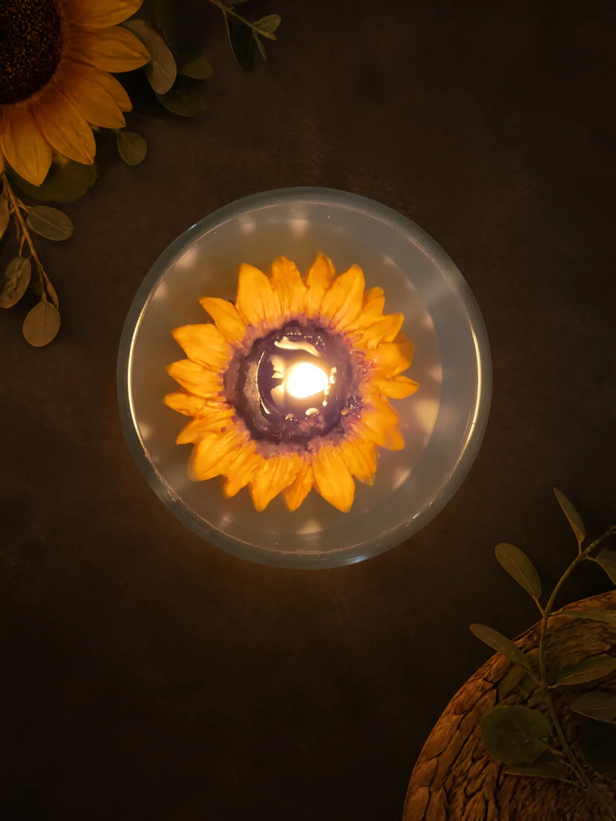 Dark top view of the burning sunflower candle and glowing wax flower